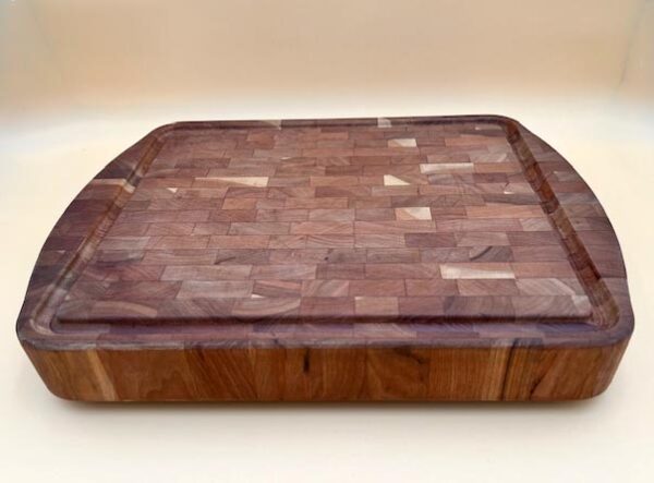 A round cherry end grain butcher block board featuring a checkered pattern of light and dark brown wood pieces, displayed on a plain white background.