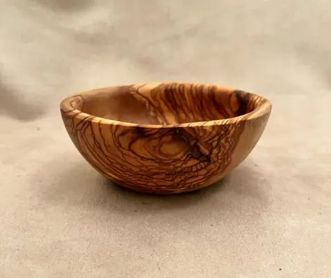 A small olive wooden bowl on a cream surface