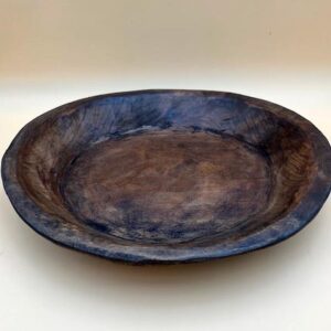 A ROUND CARVED DOUGH BOWL with a dark brown color.