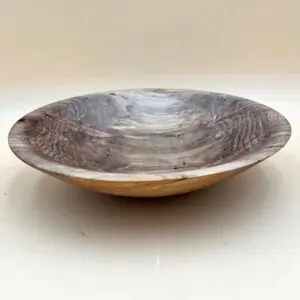 A simple Ambrosia Maple Artisan Bowl with natural grain patterns, placed on a light beige surface.