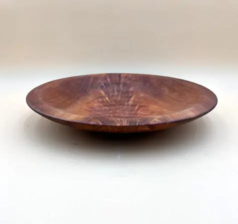 A Wild Cherry Artisan Bowl with a rich brown color and visible wood grain patterns, positioned on a light gray background.